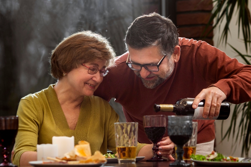 Una pareja senior disfruta del vino en su cena